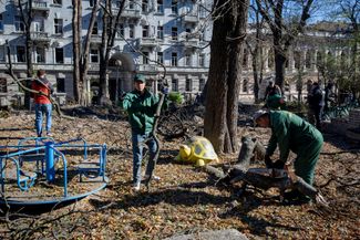 Муниципальные работники расчищают детскую площадку, пострадавшую во время российского обстрела в центре Киева