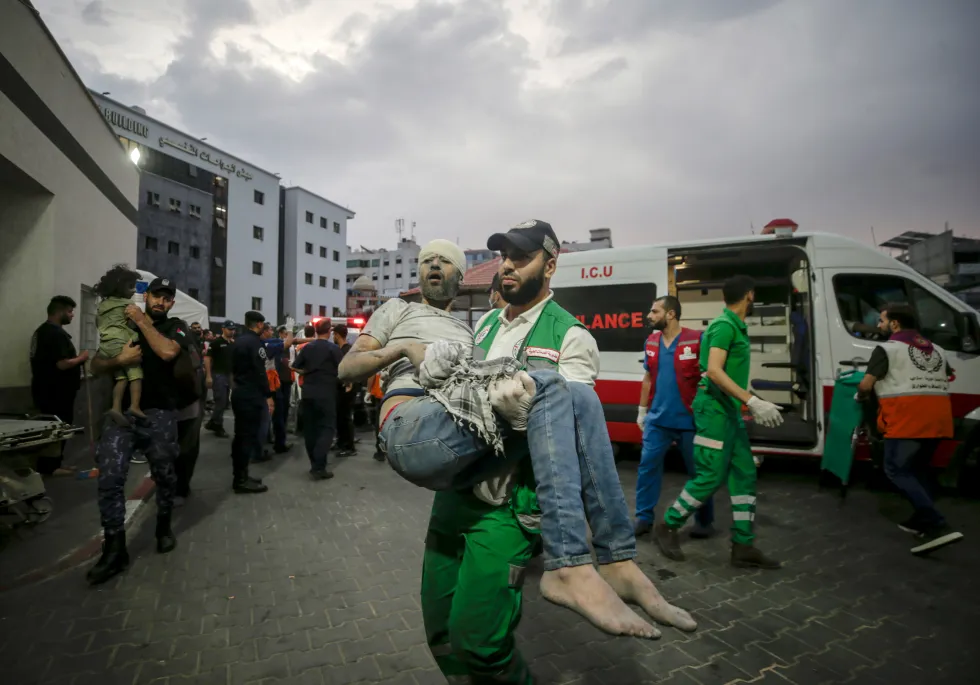 Спасатель несет раненого в больницу Аль-Шифа в Газе