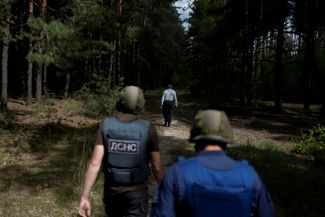 Саперы ГСЧС Украины идут в лес за жителем Бородянки, который ведет их к неразорвавшемуся снаряду