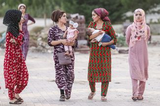 Women walk with their children in Dushanbe. August 2018.