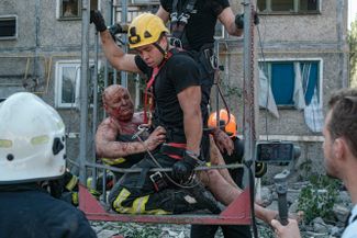 Спасатели эвакуируют раненного жителя Николаева из разрушенного многоэтажного дома.