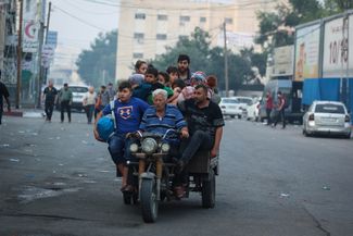 Палестинская семья едет в убежище по одной из улиц Газы