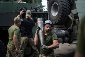Военнослужащий ВСУ несет один из таких боеприпасов калибра 155 миллиметров для гаубицы «Богдана»