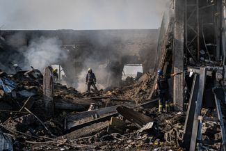 Пожарные тушат огонь на месте одного из зданий Краматорска, попавших под российский обстрел
