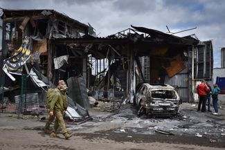 Украинские военнослужащие проходят мимо сгоревшего в результате обстрела здания в Днепре