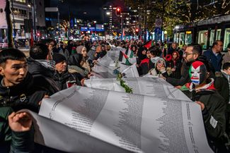 Активисты несут полотно, на котором написаны имена погибших в секторе Газа