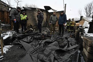 Сотрудники украинской полиции стоят перед телами погибших в результате российского удара по Харькову