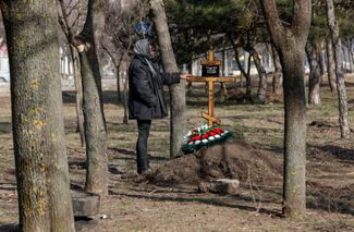 Женщина стоит рядом с могилой своей матери, погибшей в результате обстрела. 23 марта 2022 года