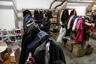 Волонтерка шелтера в комнате с одеждой, которую собрали для беженцев