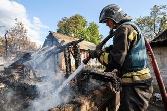 Сотрудник экстренных служб тушит пожар, возникший на территории частного жилого дома в Петровском районе Донецка после украинского обстрела