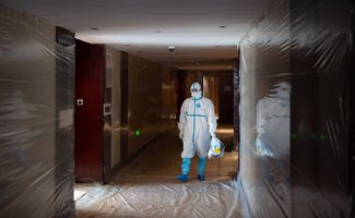 Медицинский сотрудник в коридоре гостиницы, закрытой на карантин. 31 декабря 2020 года