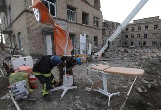 Сотрудники Государственной службы по чрезвычайным ситуациям (ГСЧС) Украины выносят медицинское оборудование из здания больницы