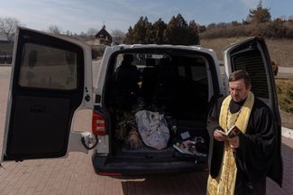 Священник отпевает неопознанные тела у крематория в Киеве