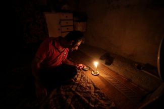 Житель Бейрута курит при свете свечи. В июле 2021 года одна из крупнейших электростанций страны отключилась на несколько дней из-за недостатка средств на закупку топлива. 10 июля 2021 года