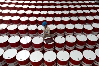 Рабочий индонезийской государственной нефтегазовой компании Pertamina маркирует бочки со смазочными материалами. Индонезия, Чилочап, 6 ноября 2017 года