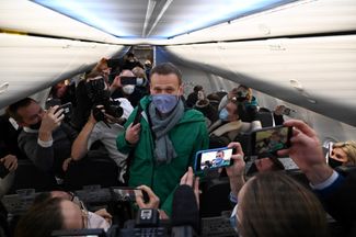 В конце декабря 2020-го Навальный опубликовал видеозапись своего разговора с участником команды отравителей. К тому моменту политик уже три месяца проходил реабилитацию в Германии; российские власти говорили, что его лечение — попытка сбежать из-под условного срока по делу «Ив Роше». Несмотря на угрозу ареста, в январе 2021-го Навальный объявил, что вскоре прилетит в Россию. Позже он рассказывал, что у него не было сомнений, возвращаться или нет, он не представлял себе жизни в эмиграции. Алексей Навальный в самолете авиакомпании «Победа» 17 января 2021 года