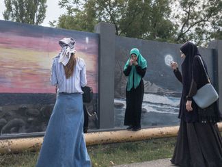Девушки фотографируются на фоне рисунков в Грозном