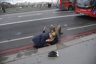 Женщина оказывает помощь пострадавшему на Вестминстерском мосту
