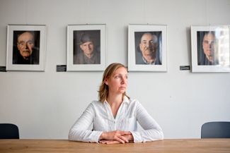 Coordinator Ragna Vogel at the Kontakte-Kontakty office. On the wall behind her are portraits of people who survived German captivity during World War II. 