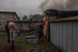 Пожарный пытается попасть в гараж, загоревшийся в результате обстрела российской артиллерией. Харьков