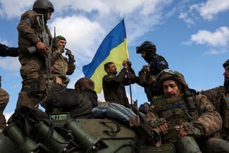 Украинские военные устанавливают национальный флаг на бронетранспортере на дороге возле Лимана Донецкой области