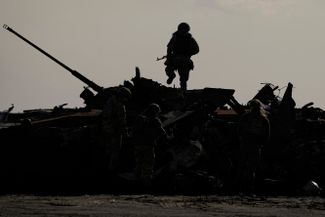 Украинский военнослужащий на уничтоженной российской военной технике в Буче, Киевская область