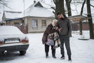Житель Часова Яра Сергей ведет свою 75-летнюю тещу Раису к автомобилю во время эвакуации