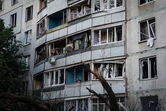 Житель Харькова выглядывает с балкона своей квартиры в многоэтажном доме, поврежденном российской ракетой. Российские войска продолжают обстрелы жилых кварталов Харькова, 7 июля погибли трое мирных жителей города, еще пятеро ранены