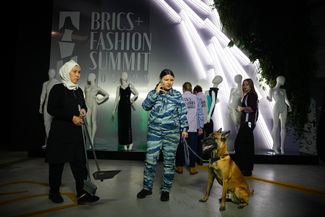 Сотрудница службы безопасности с собакой-ищейкой на Саммите моды БРИКС+ в московском парке «Зарядье», 28 ноября 2023 года.