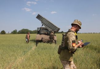 Украинские артиллеристы готовятся к стрельбе из реактивной системы залпового огня БМ-21 «Град» в поле возле Изюма, к югу от Харькова