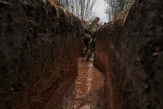 Украинский пехотинец идет по траншее после дождя