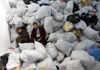 Волонтеры отдыхают на мешках с одеждой, пожертвованной для эвакуированных. Львов