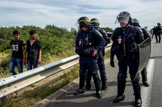 Французские полицейские из подразделения по борьбе с массовыми беспорядками на дороге, которая ведет к причалу паромов в порту Кале