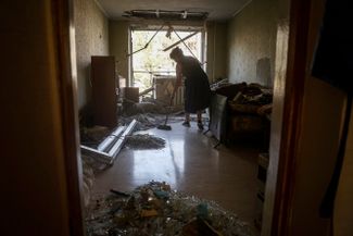 Женщина убирает квартиру после того, как в ее дом в Краматорске попала российская ракета