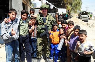A Russian soldier surrounded by children in a suburb outside Damascus