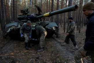 Украинские военные достают из российского танка аккумулятор, чтобы зарядить его