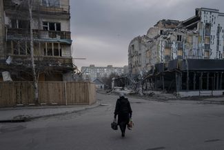Жительница Покровска проходит мимо домов, разрушенных во время обстрелов