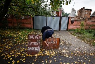 58-летняя Валентина Ивановна устанавливат табличку с просьбой пожертвовать ей цемент на восстановление дома. Он был разрушен во время боев за город. 