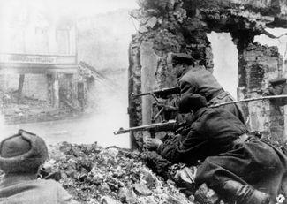 Soviet troops fighting in the Königsberg suburbs in 1945. The officer in the background is firing a German submachine gun.