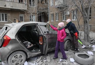 Жители Харькова осматривают свой автомобиль, поврежденный в результате российской атаки