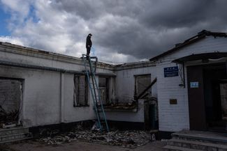 Судебно-медицинский эксперт на крыше здания, которое российские военные использовали в качестве местного штаба
