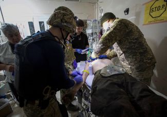 Медицинские работники оказывают первую помощь раненому бойцу ВСУ