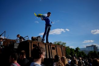 Молодой человек с украинским флагом на разбитом российском танке