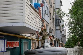 Украинские военные передают из лодки пакет с гуманитарной помощью жителю Херсона Сергею