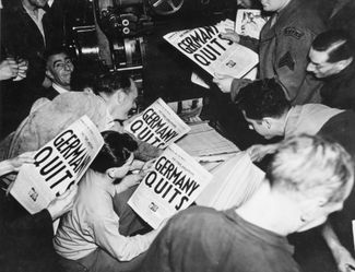 Солдаты союзников читают только что сделанные оттиски Stars and Stripes (газеты министерства обороны США), в которых объявляется о капитуляции Германии во Второй мировой войне. Лондон, 7 мая 1945 года.