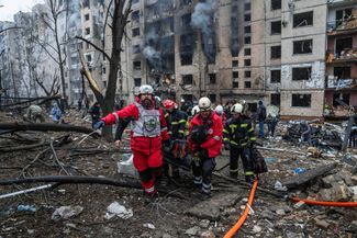 Добровольцы и спасатели Красного Креста выносят человека из здания, поврежденного в результате российской ракетной атаки