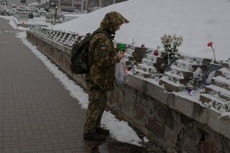 Украинский военнослужащий зажигает свечу у мемориала в память о погибших в столкновениях на майдане в Киеве. 21 ноября 2022 года