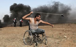 Палестинец атакует израильских солдат во время столкновений у границы сектора Газа, 11 мая 2018 года.