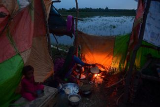 Женщина готовит на костре лепешки в импровизированном лагере для людей, которых наводнение лишило крова. Округ Наушахро-Ферозе, провинция Синд