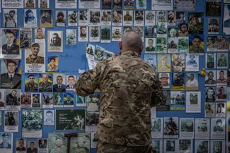 Украинский военный размещает фотографию погибшего на фронте товарища на Стене памяти возле здания МИД Украины